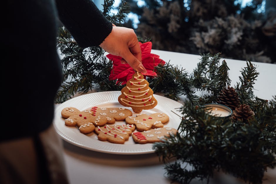 아름답게 장식된 테이블 위에서 한 손이 축제 분위기의 진저브레드 쿠키를 고르는 모습은 연말연시 축하 행사에 딱 어울립니다.