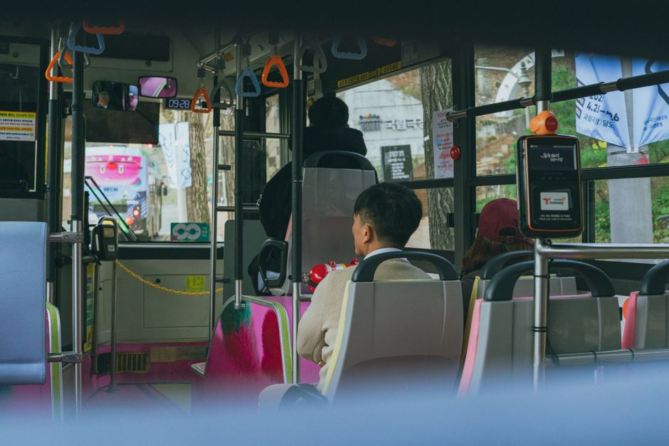 버스 내부 좌석 시트와 창문에 부착된 광고를 유심히 살펴보는 승객의 모습